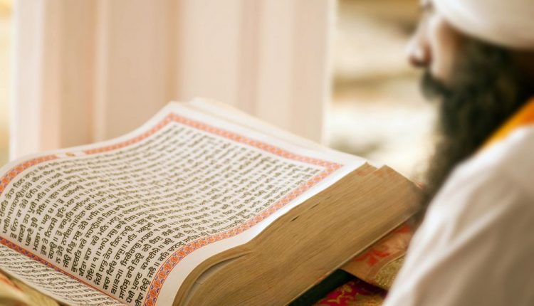 مردی دیندار در حال خواندن کتاب مقدس «گورو گرانت صاحب»، کتاب مقدس آیین سیک