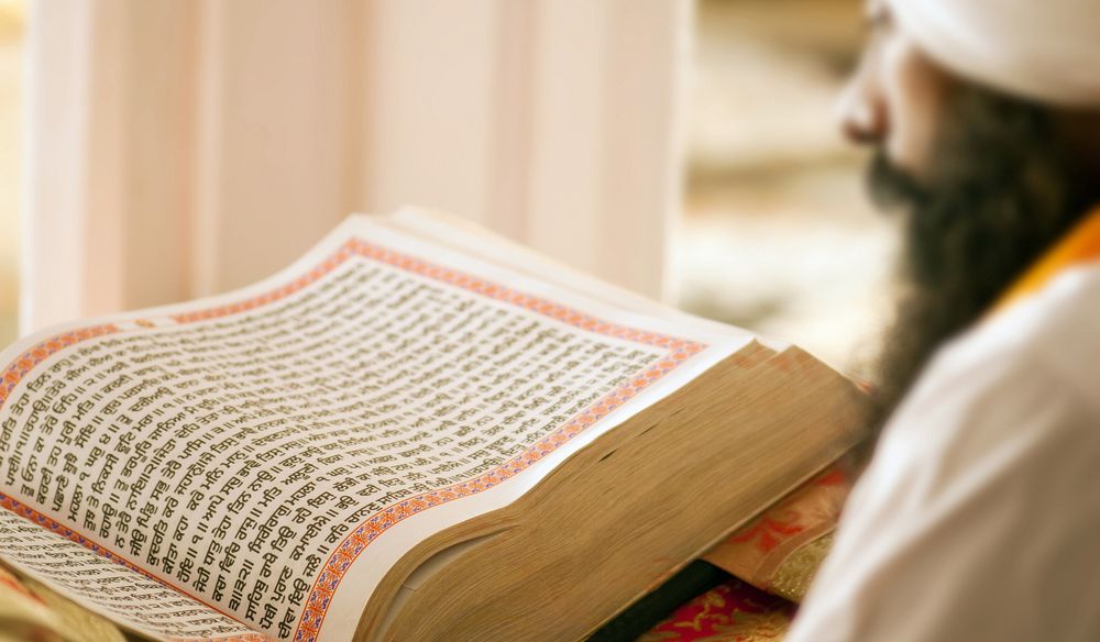 مردی دین‌دار در حال خواندن کتاب مقدس «گورو گرانت صاحب»، کتاب مقدس آیین سیک